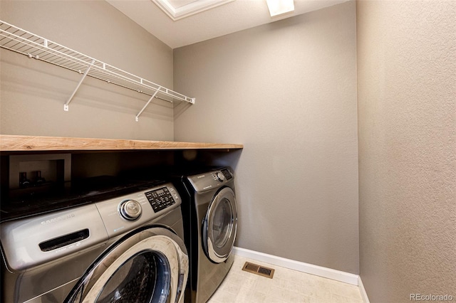 laundry room with laundry area, visible vents, baseboards, tile patterned floors, and washing machine and dryer