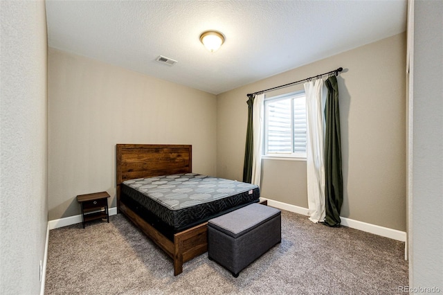 carpeted bedroom featuring a textured ceiling, visible vents, and baseboards