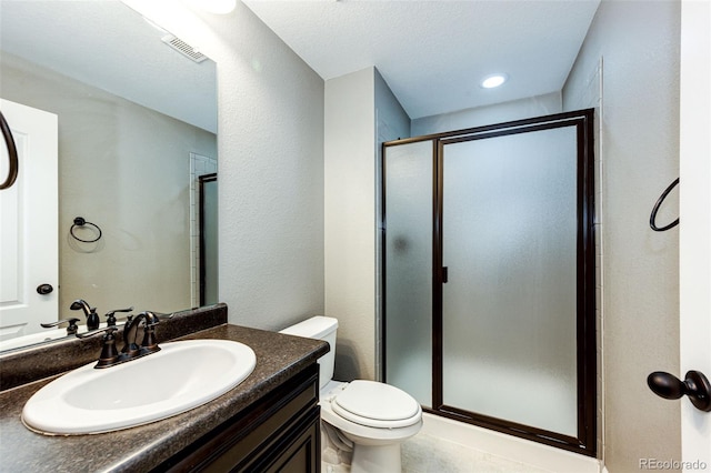 bathroom featuring a stall shower, visible vents, a textured wall, toilet, and vanity