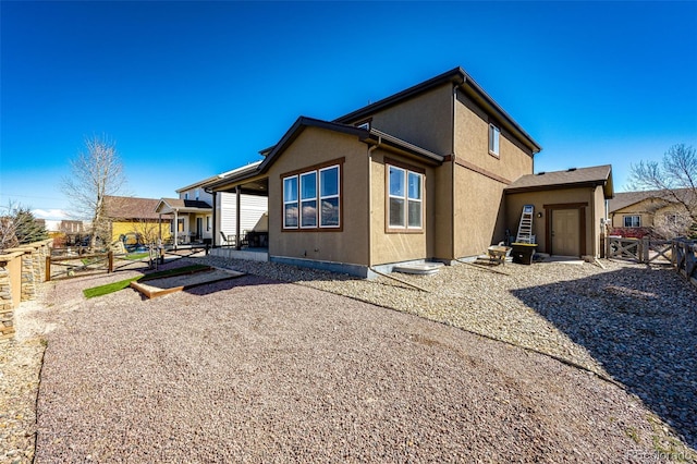 back of house featuring a patio area, a gate, fence, and stucco siding