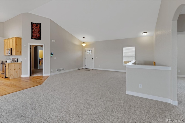 unfurnished living room with light carpet and high vaulted ceiling