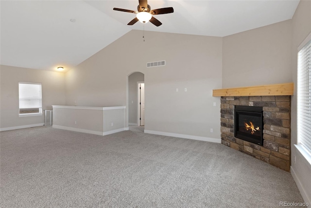 unfurnished living room with ceiling fan, a stone fireplace, carpet floors, and lofted ceiling