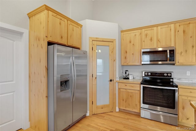 kitchen with light brown cabinetry, appliances with stainless steel finishes, and light hardwood / wood-style flooring