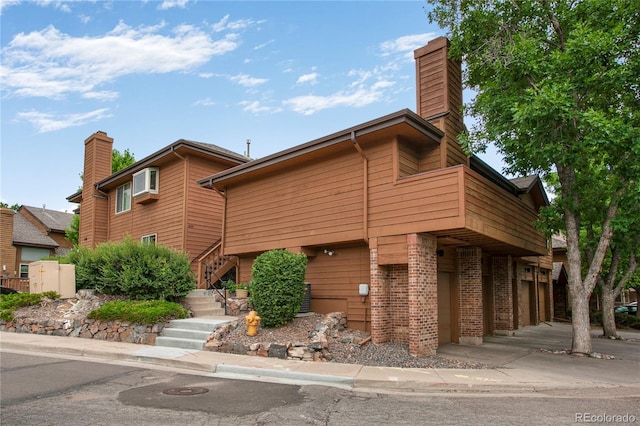 5555 E Briarwood Ave Unit 603, Centennial, CO 80122 - view of front of property with brick siding, a chimney, stairs, a balcony, and a garage