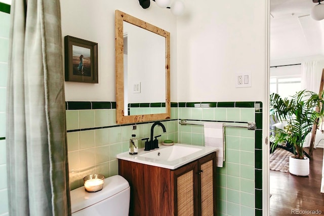 4422 W 27th Ave, Denver, CO 80212 - half bathroom featuring toilet, tile walls, vanity, a wainscoted wall, and wood finished floors