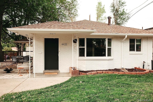 4422 W 27th Ave, Denver, CO 80212 - view of front facade featuring brick siding, a front lawn, a shingled roof, and a patio