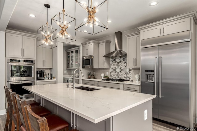 5964 E 141st Ave, Thornton, CO 80602 - kitchen featuring built in appliances, wall chimney range hood, a sink, dark wood finished floors, and gray cabinetry