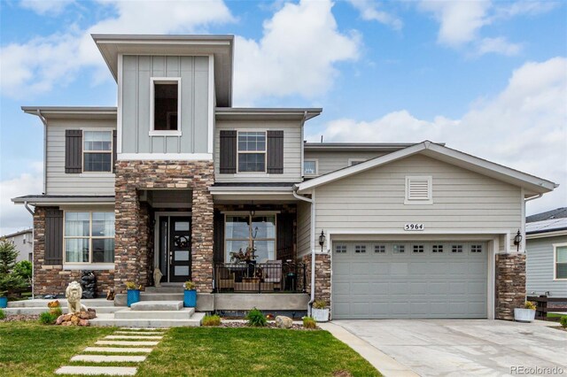 5964 E 141st Ave, Thornton, CO 80602 - view of front of house featuring stone siding, a front yard, driveway, and covered porch