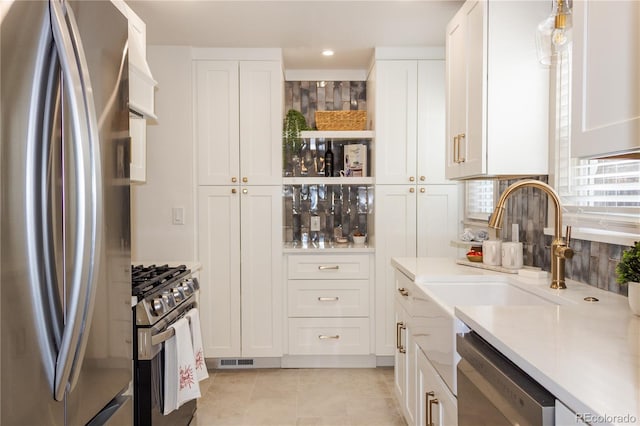 kitchen with light tile patterned floors, sink, appliances with stainless steel finishes, backsplash, and white cabinets