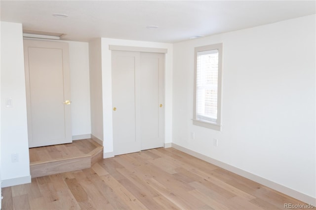 unfurnished bedroom with a closet and light wood-type flooring