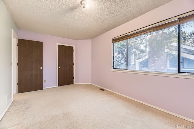 unfurnished bedroom featuring light colored carpet and a textured ceiling