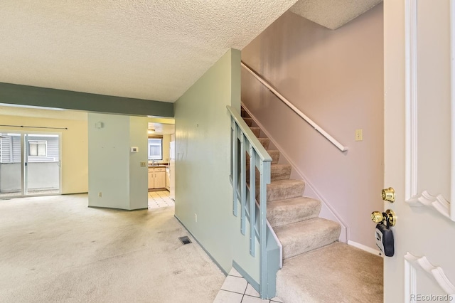 staircase featuring carpet and a textured ceiling