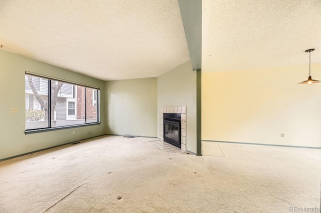 unfurnished living room with a textured ceiling, a tiled fireplace, light colored carpet, and lofted ceiling