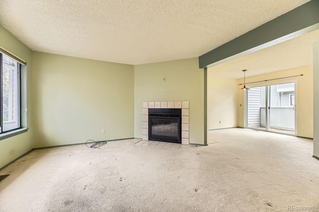 unfurnished living room featuring a fireplace, light carpet, plenty of natural light, and a textured ceiling