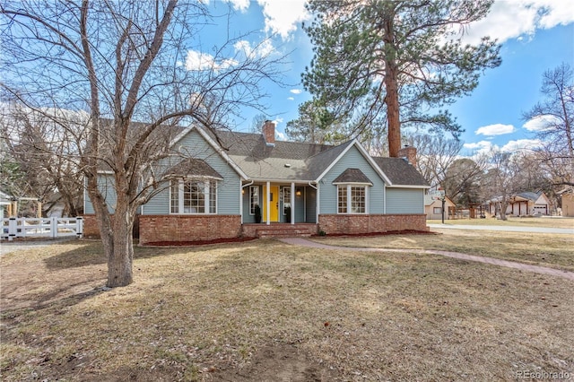 ranch-style home with brick siding, a chimney, a front yard, and fence