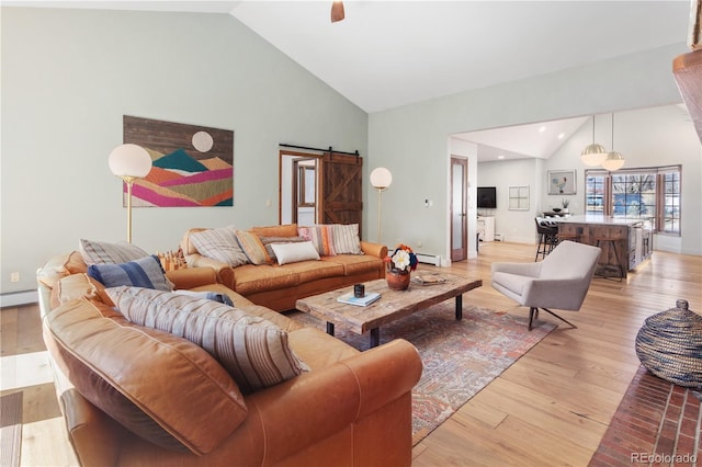 living area featuring light wood finished floors, a barn door, recessed lighting, high vaulted ceiling, and a baseboard radiator