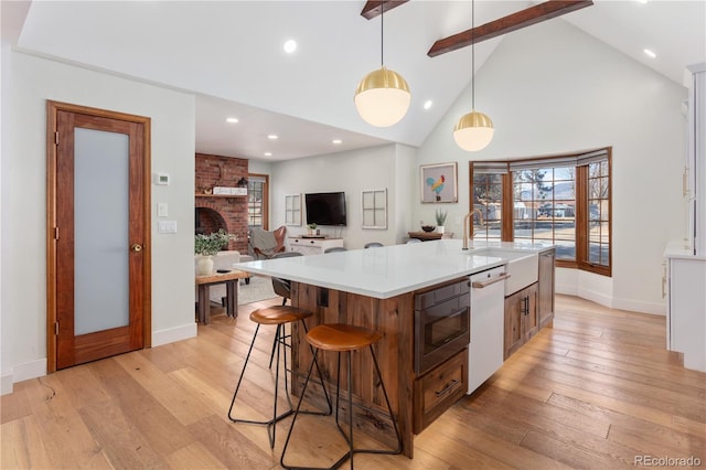 kitchen with a brick fireplace, built in microwave, light countertops, light wood-style flooring, and white dishwasher