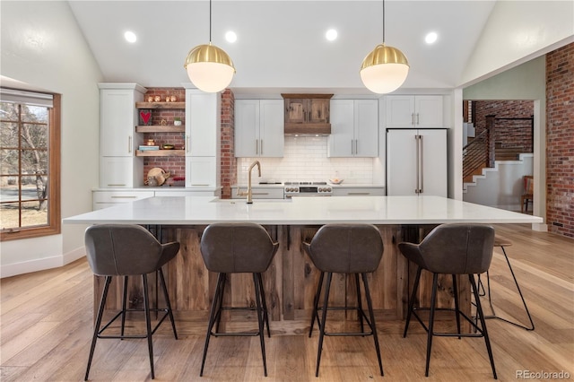 kitchen featuring high end refrigerator, a sink, stainless steel range oven, and vaulted ceiling