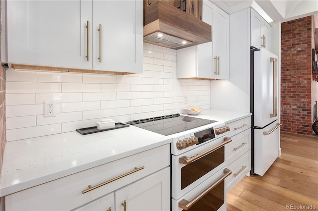 kitchen featuring white appliances, light wood-style floors, premium range hood, and light countertops