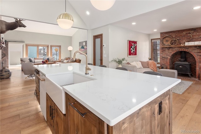 kitchen featuring open floor plan, light wood-style flooring, a sink, and a kitchen island with sink