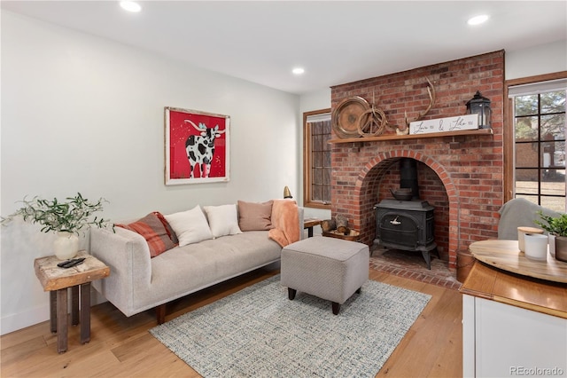 living room with recessed lighting, baseboards, light wood-style flooring, and a wood stove