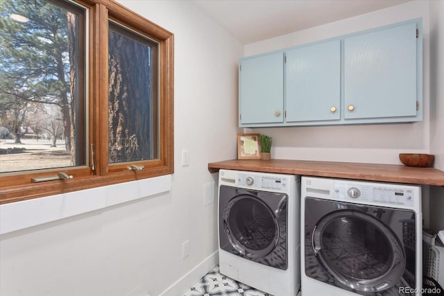 laundry area featuring baseboards, cabinet space, and washing machine and clothes dryer