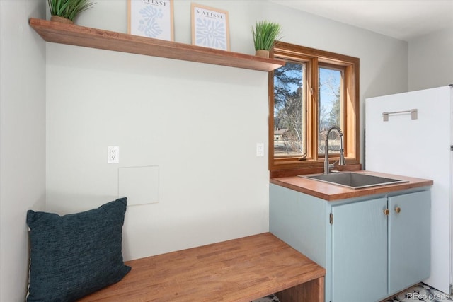 interior space featuring blue cabinetry, freestanding refrigerator, and a sink