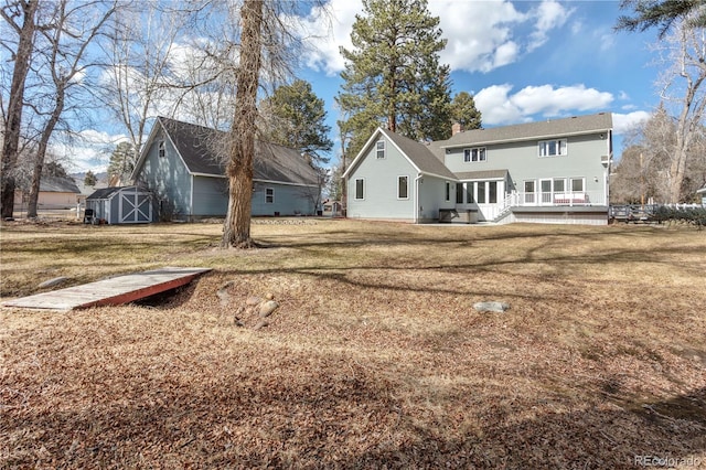 back of house with an outbuilding, a shed, a yard, a wooden deck, and a chimney