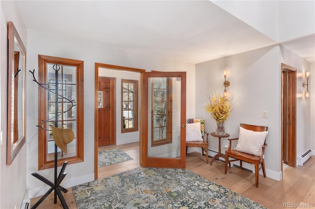 foyer with baseboards, a baseboard heating unit, and light wood-style floors