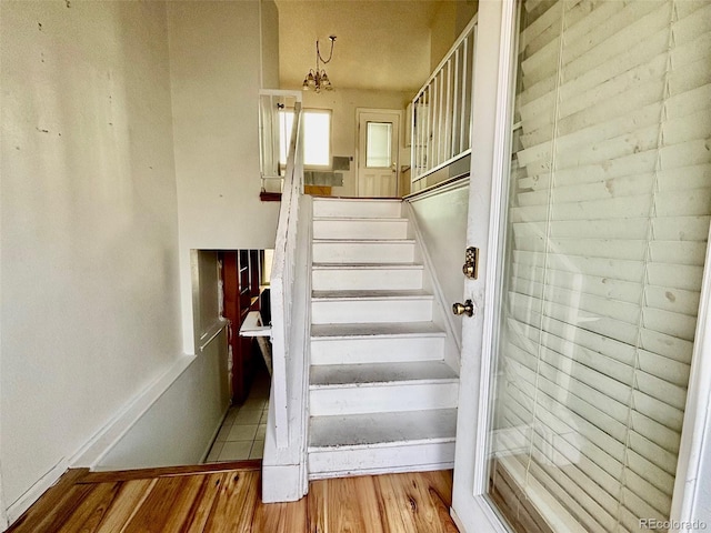 stairway featuring wood-type flooring and a chandelier