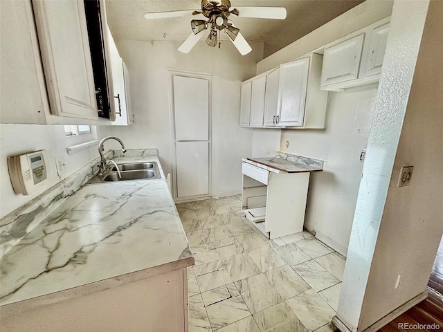 kitchen with ceiling fan, white cabinetry, and sink