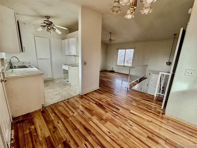 kitchen featuring white cabinets, a textured ceiling, ceiling fan with notable chandelier, and sink