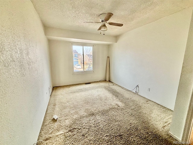 carpeted spare room with ceiling fan and a textured ceiling