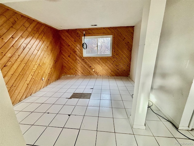 empty room with wooden walls and light tile patterned flooring