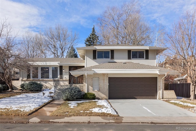 split level home featuring driveway, a shingled roof, an attached garage, fence, and brick siding