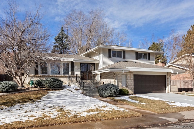 tri-level home with concrete driveway, brick siding, an attached garage, and a shingled roof