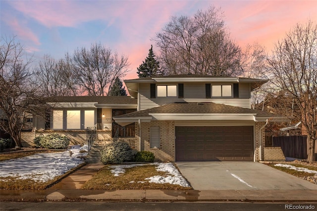 view of front of house featuring a garage, a shingled roof, concrete driveway, and brick siding