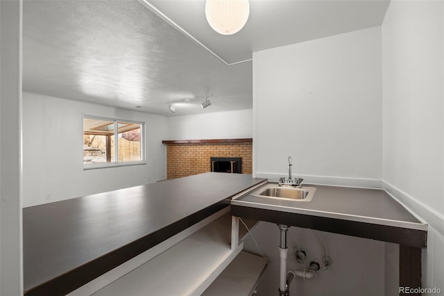 interior space with rail lighting, a textured ceiling, and a sink