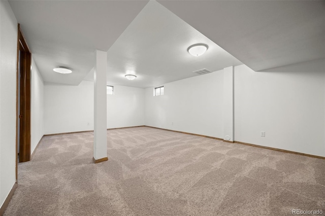 below grade area featuring visible vents, light carpet, and baseboards