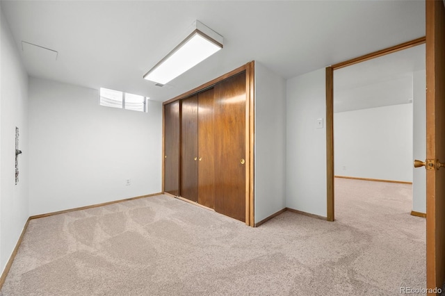 unfurnished bedroom with light carpet, a closet, and baseboards