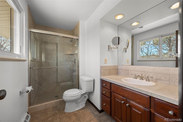 bathroom featuring toilet, vanity, baseboards, a shower stall, and tasteful backsplash