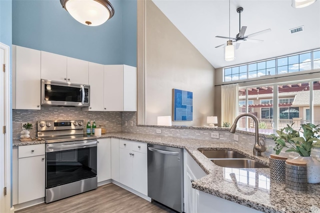8626 Gold Peak Dr Unit B, Highlands Ranch, CO 80130 - kitchen featuring stainless steel appliances, high vaulted ceiling, ceiling fan, white cabinets, and light wood finished floors