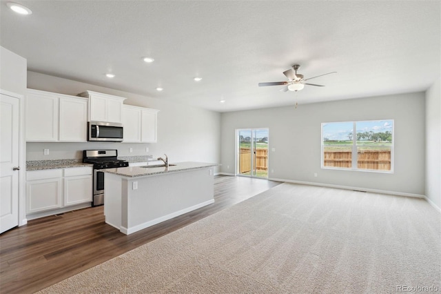 kitchen featuring light stone countertops, white cabinetry, sink, a kitchen island with sink, and appliances with stainless steel finishes