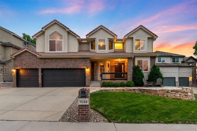 7038 Russell Ct, Arvada, CO 80007 - view of front facade with brick siding, a porch, a front yard, stucco siding, and an attached garage
