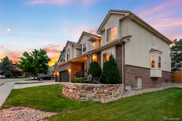 7038 Russell Ct, Arvada, CO 80007 - property exterior at dusk featuring driveway, brick siding, a lawn, and stucco siding