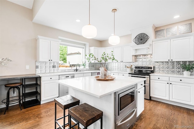 7038 Russell Ct, Arvada, CO 80007 - kitchen featuring stainless steel appliances, a warming drawer, a kitchen breakfast bar, decorative backsplash, and white cabinetry