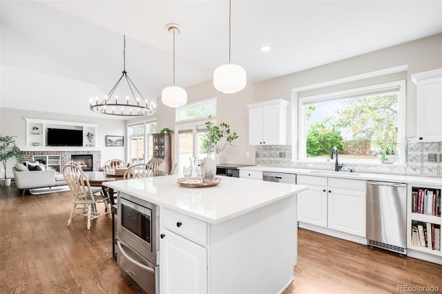 7038 Russell Ct, Arvada, CO 80007 - kitchen featuring a sink, a warming drawer, stainless steel appliances, a fireplace, and tasteful backsplash