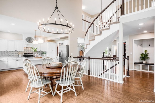 7038 Russell Ct, Arvada, CO 80007 - dining area with light wood-type flooring, a high ceiling, a chandelier, and recessed lighting