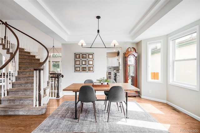 7038 Russell Ct, Arvada, CO 80007 - dining space featuring a tray ceiling, stairs, and light wood finished floors