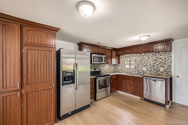 4730 S Huron St, Englewood, CO 80110 - kitchen with appliances with stainless steel finishes, light wood-type flooring, decorative backsplash, and light stone countertops